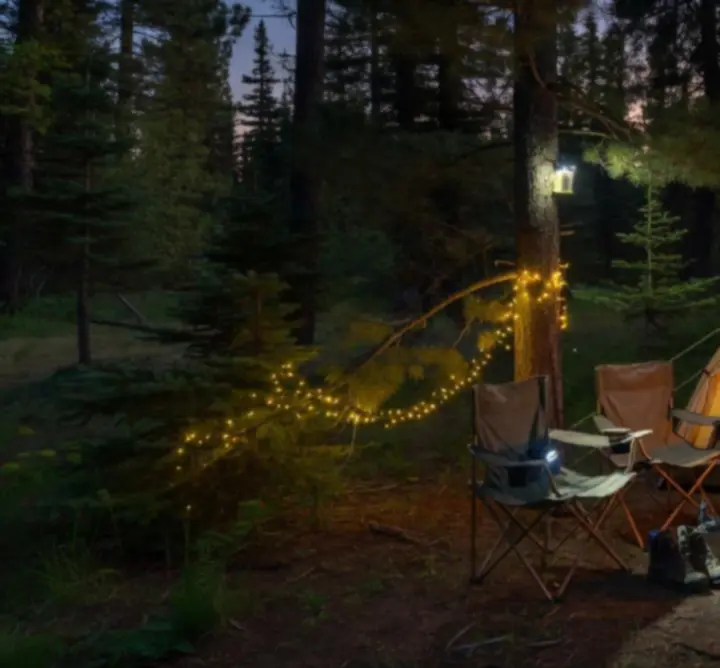 Kempinglámpák és fejlámpák világítanak egy sátor körül éjszaka